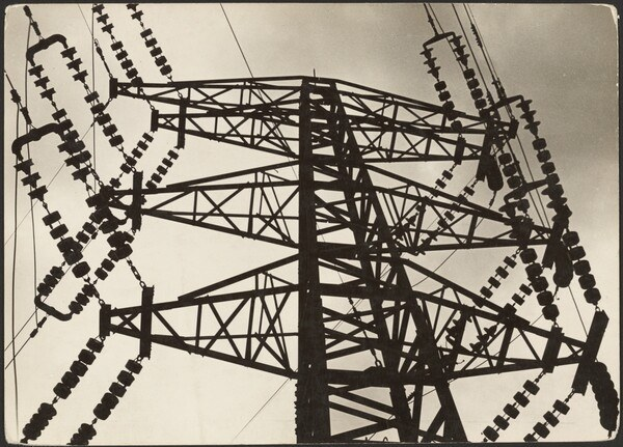 Schwarz-weißes Foto einer Hochspannungsleitung mit Turm und Dr├Âhten vor einem Himmel, mit Text unten.