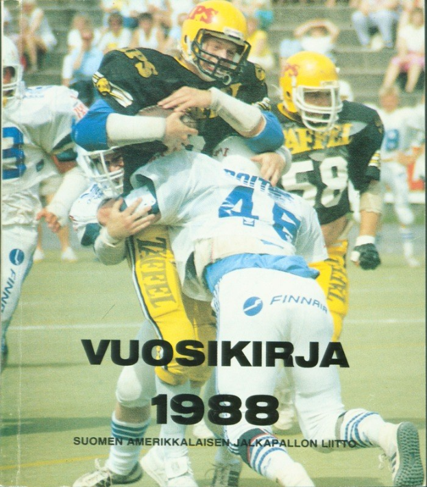 Gruppe von Menschen in Sportbekleidung und Helmen, die American Football auf einem Feld spielen, mit Zuschauern auf den Stufen im Hintergrund; Text unten lautet "Vuosikirja 1988 - Suomen Amerikkaisen Jalkapallon Liitto".