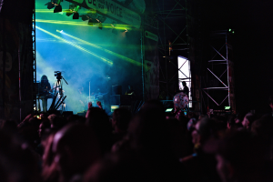 Ein volles Konzert mit Performern auf der Bühne, beleuchtet von Scheinwerfern und einem Banner im Hintergrund.