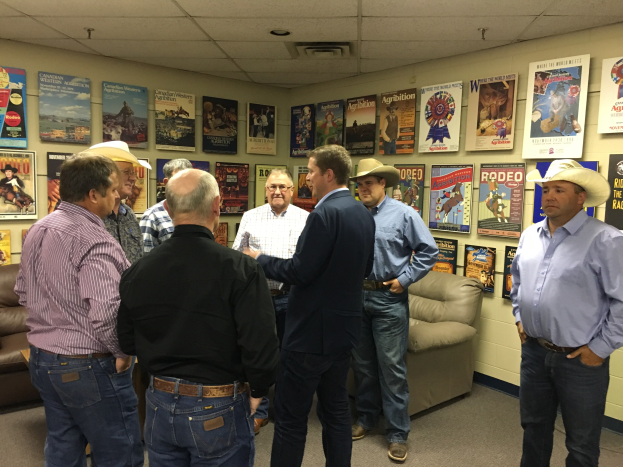 Gruppe von Männern in einem Raum mit Sofas, Postern an den Wänden und Deckenleuchten, die sich unterhalten.