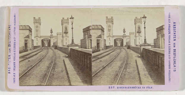 Schwarz-weiß-Stereofoto einer Eisenbahnbrücke in Köln, Deutschland, mit Eisenbahnschienen, Wänden, Pfählen, Statuen, Himmel und Text.