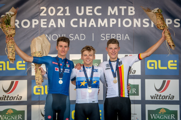 Drei medaillenreiche Radrennfahrer auf einem Podium bei den 2021 UEC MTB Europameisterschaften, jeder hält einen Blumenstrauß.