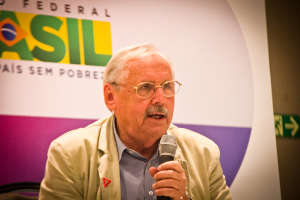 Eine Person, die in ein Mikrofon spricht und hinter sich ein Banner mit der Aufschrift 'Bundes' hat.