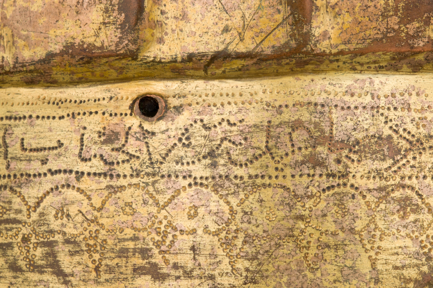 Nahaufnahme einer rostigen Metalloberfläche mit einem Loch und schwachem Text.