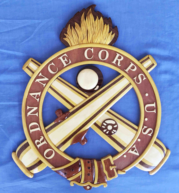 Holzschild mit "Ordnance Corps"-Text, das einen geschnitzten weißen Stern auf einem navyblauen Hintergrund mit goldener Umrandung zeigt, auf blauem Tuch montiert.