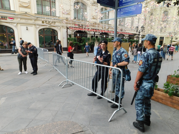 Polizeibeamte in Uniform stehen hinter Barrieren und blicken auf eine Menge, einige halten Waffen, während sie eine Anti-Terror-Operation in Wien, Österreich, durchführen, mit Gebäuden, Bäumen und Laternen im Hintergrund.