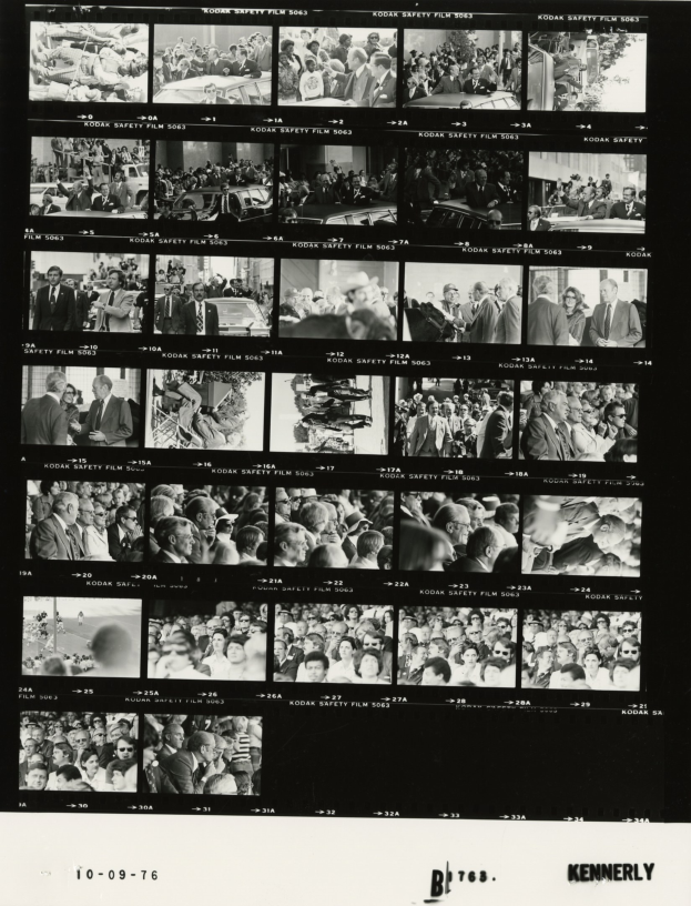 Schwarzes und weißes Foto einer vielfältigen Menschenmenge, die fröhlich in Richtung eines Fernsehbildschirms schaut, mit Text unten.