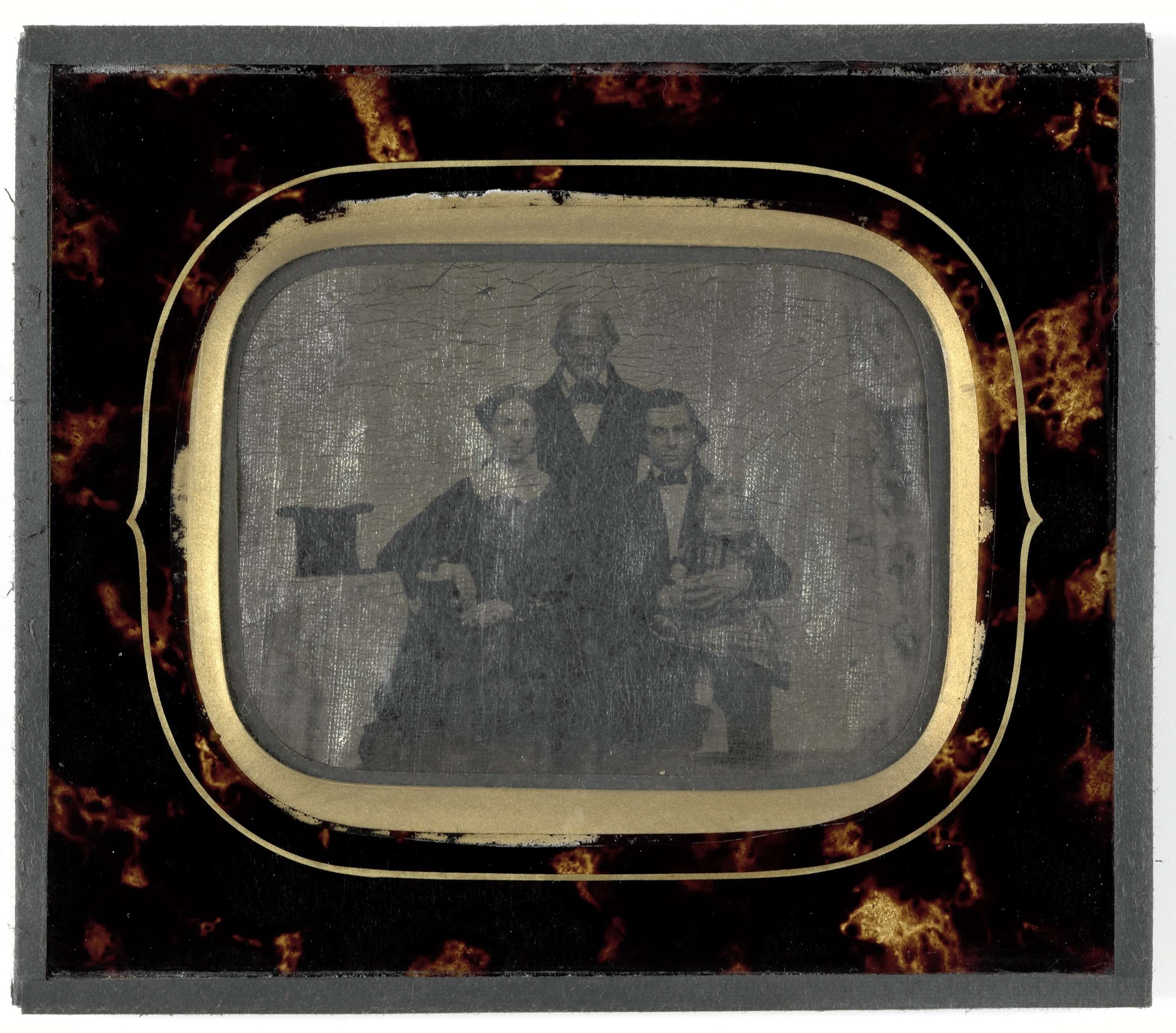 Schwarz-weißes Foto eines Mannes in Anzug und Krawatte und einer Frau in unbekannter Kleidung, die vor einem alten Fernseher stehen und ernst schauen.