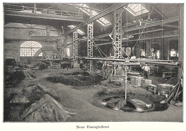 Schwarzes und weißes Foto einer Fabrik mit Arbeitern, die Maschinen bedienen, umgeben von Metallstangen und -pfosten, beschriftet mit "Neue Eisenglebeerei, die erste Fabrik Deutschlands."