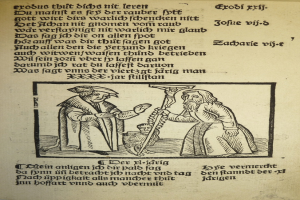 Ein bedrucktes Papier in einer fremden Sprache mit zwei Männern im Hintergrund, möglicherweise aus einem Lehrbuch.