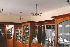 Ein Apothekeninneres mit Holzschränken, die mit Medikamenten gefüllt sind und von der Decke hängenden Kronleuchtern, das gut sortiert und ordentlich erscheint.