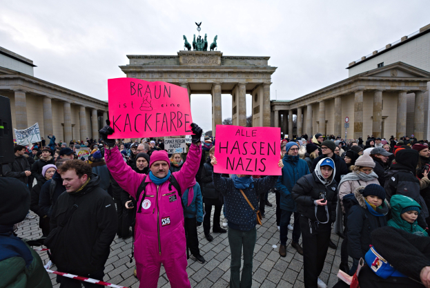 Eine Gruppe von Menschen demonstriert vor dem Brandenburger Tor in Berlin mit Schildern gegen die Anti-Nazis-Bewegung der deutschen Regierung.