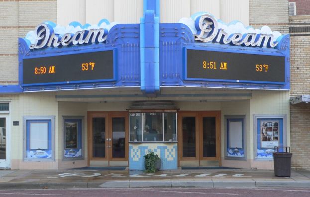 Außenansicht des Dream Theaters in St. Louis, Missouri, mit Glastüren und -fenstern, einer Schautafel, einem Müllcontainer, einem Topf mit einer Pflanze und einer Straße unten.