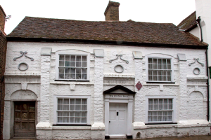 Ein weißes Haus mit einem braunen Dachziegel und einem Schornstein.