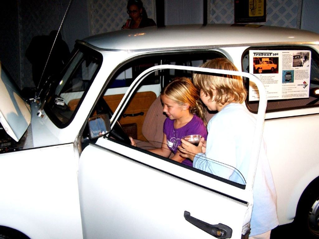 Zwei Kinder versuchen in ein Auto mit anderen Menschen in der Nähe einzusteigen.