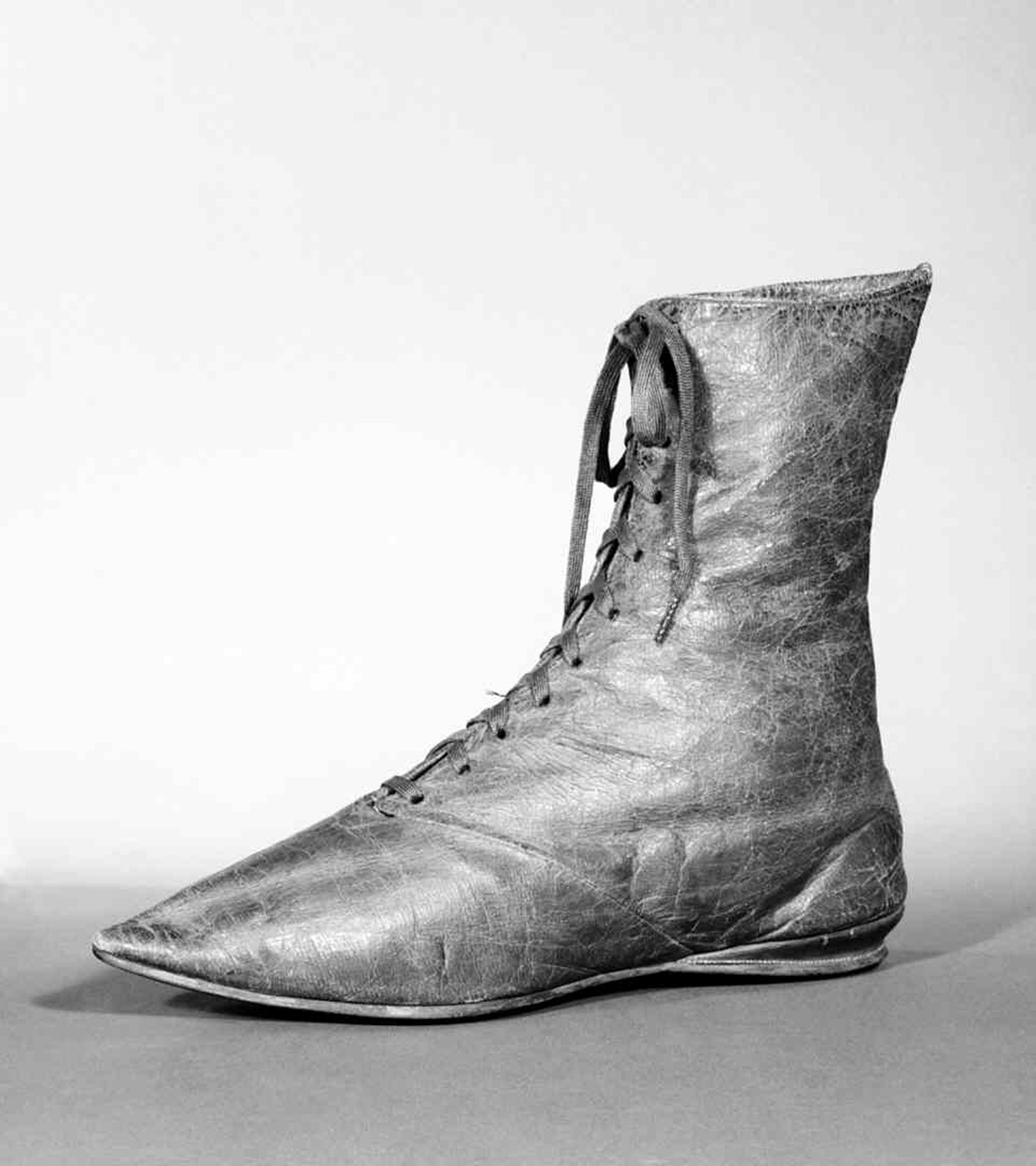 Schwarzes und weißes Foto eines Paares abgenutzter Lederschuhe mit gerundeten Zehen, niedrigen Absätzen und ordentlich gebundenen Schnürsenkeln, die das gealterte Leder aus dem späten 19. Jahrhundert zeigen.