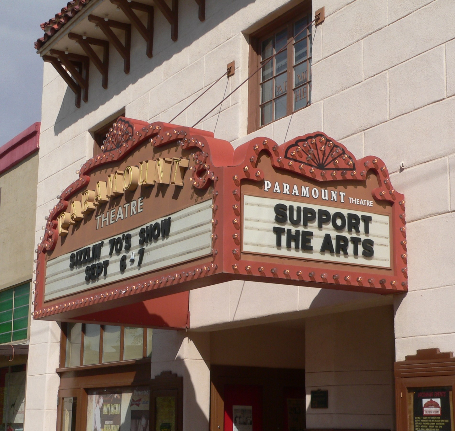 Außenansicht des Paramount Theatre in Sacramento, Kalifornien, mit Glasfenstern und -türen sowie einer 'Support the Arts'-Schrifttafel und einem sichtbaren Himmel im Hintergrund.